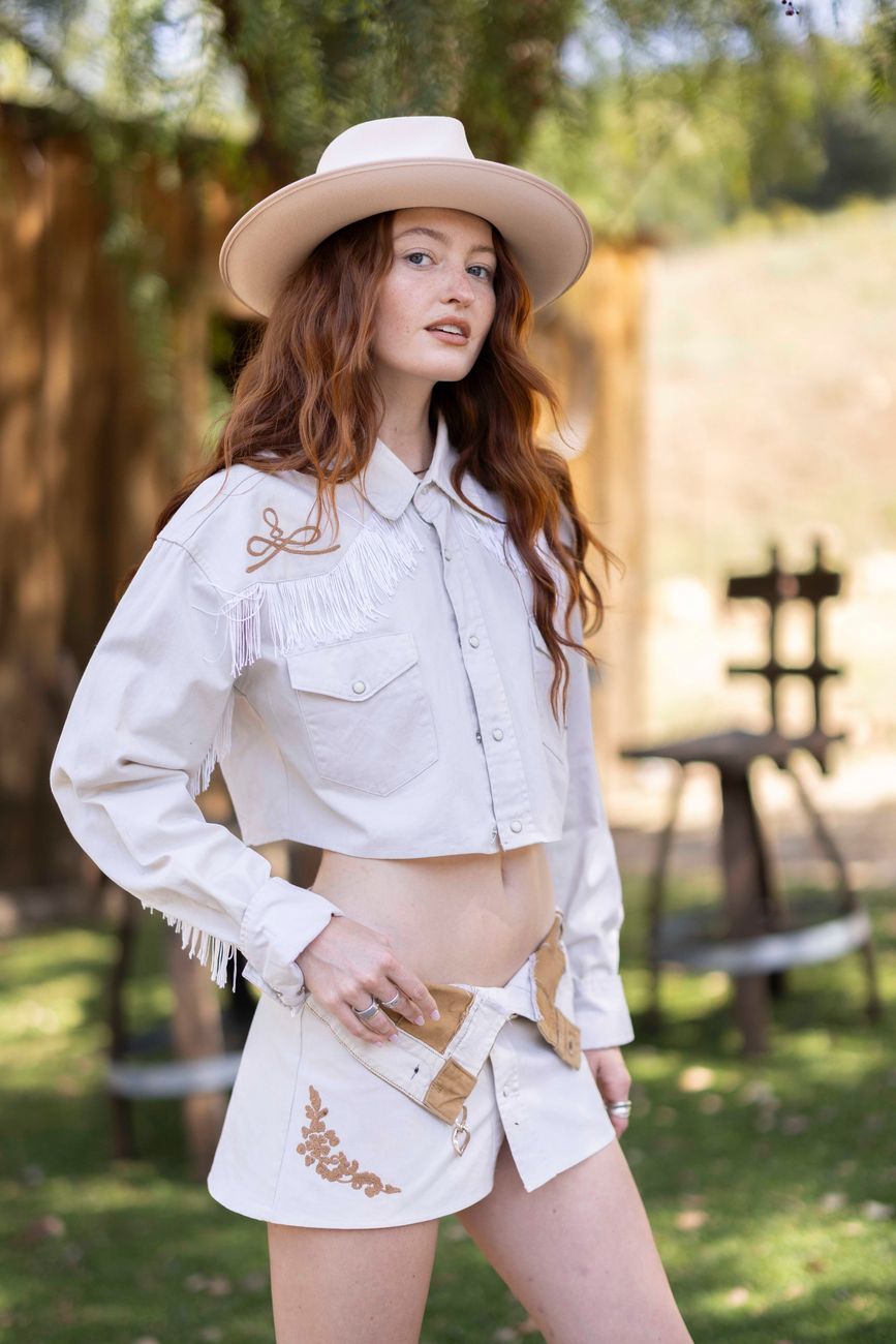 Model in a white fringe western shirt and embroidered skirt